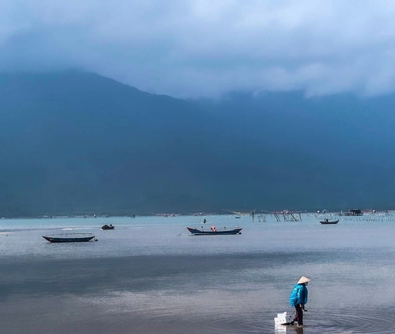 Calm sea with small boats and a cloudy sky.