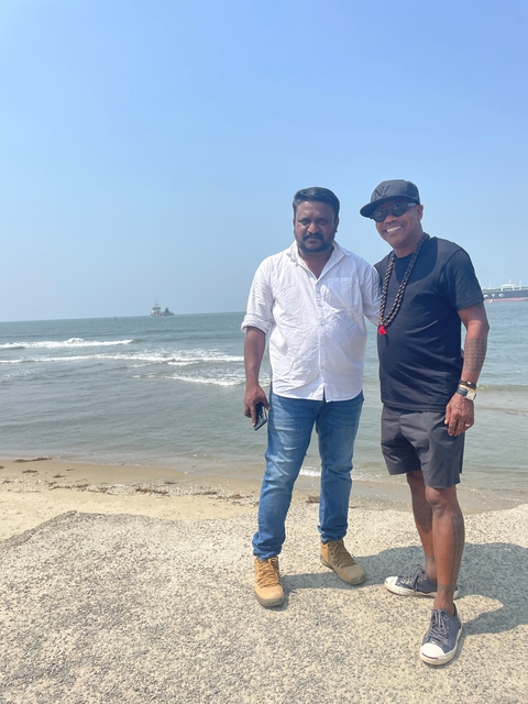 Two men at a beach with the ocean in the background.
