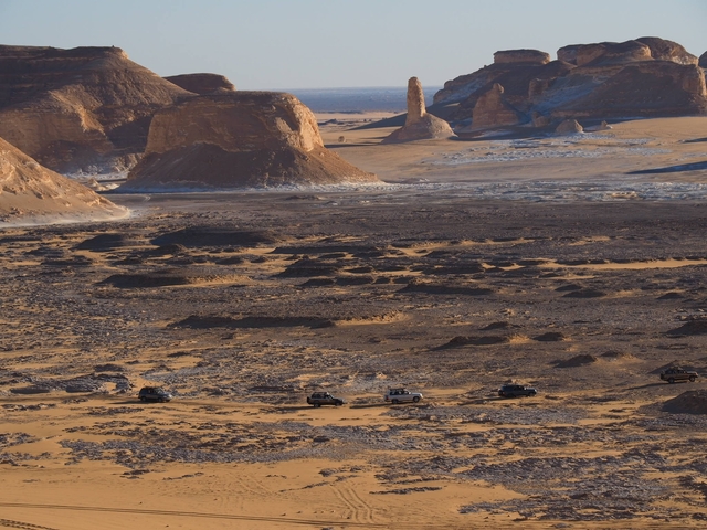 Dramatic desert landscape with vehicles on a journey.