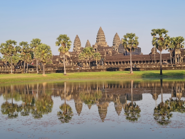       View of Angkor Wat temple reflected in a tranquil pond.
  