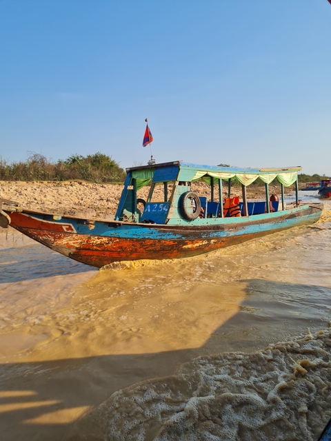       A colorful traditional boat in murky waters.
  