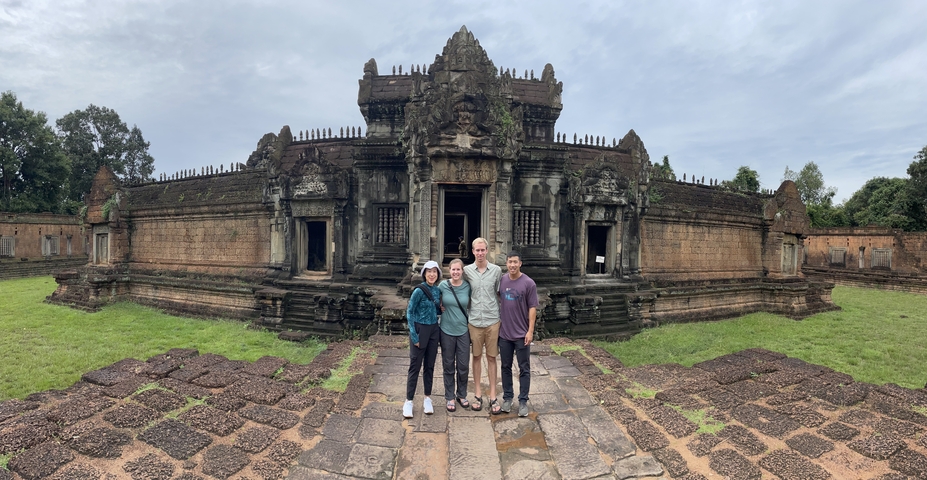 Four people posing in front of a historic Cambodian temple.