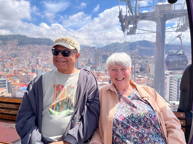 People smiling in a cable car with city view