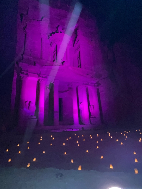 Pink-lit stone facade of an ancient structure at night.