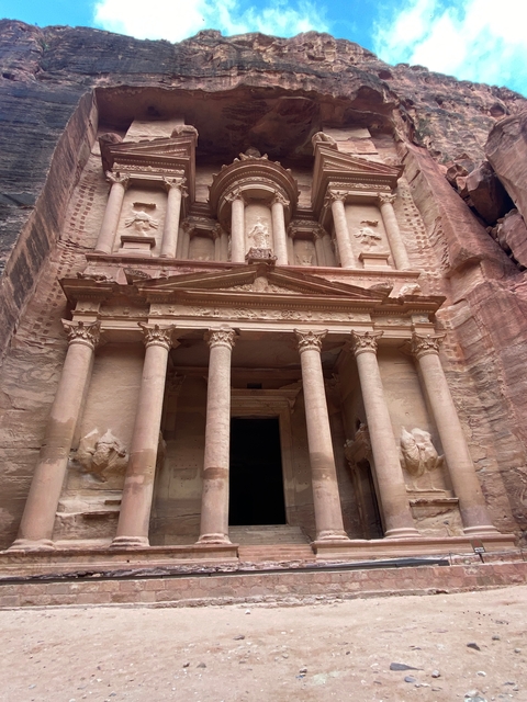       Stone-carved facade of a temple with columns and sculptures.
  