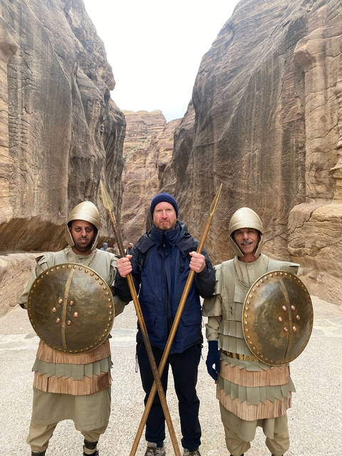 Group photo with two individuals in historic warrior costumes in a narrow canyon.