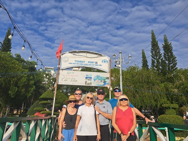 Group of tourists posing by a sign at a tourist port.