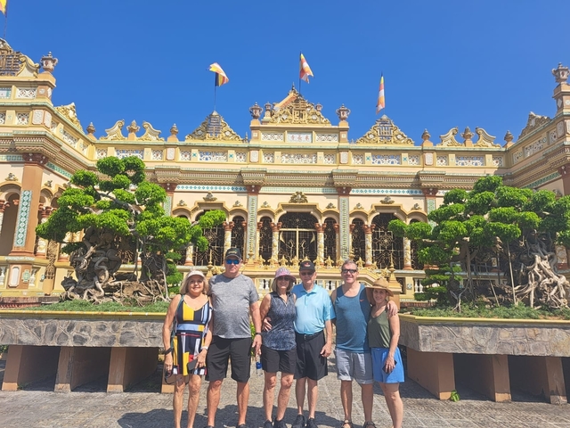 Tourists posing in front of a decorative temple.