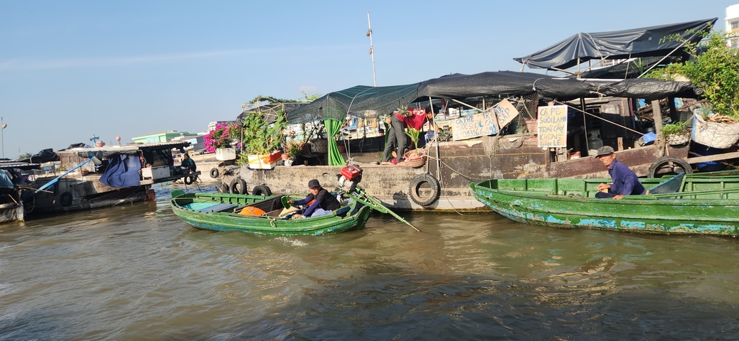 Row of boats on a waterway with market stalls along the bank.