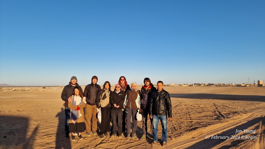       Group of people posing in a desert.
  