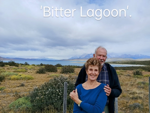 Couple posing with a lake and mountains in the background.