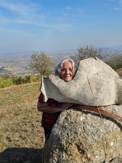       Woman posing behind a stone sculpture with landscape view.
  