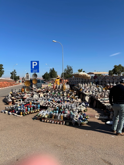 Outdoor market stall selling Moroccan pottery and goods.
