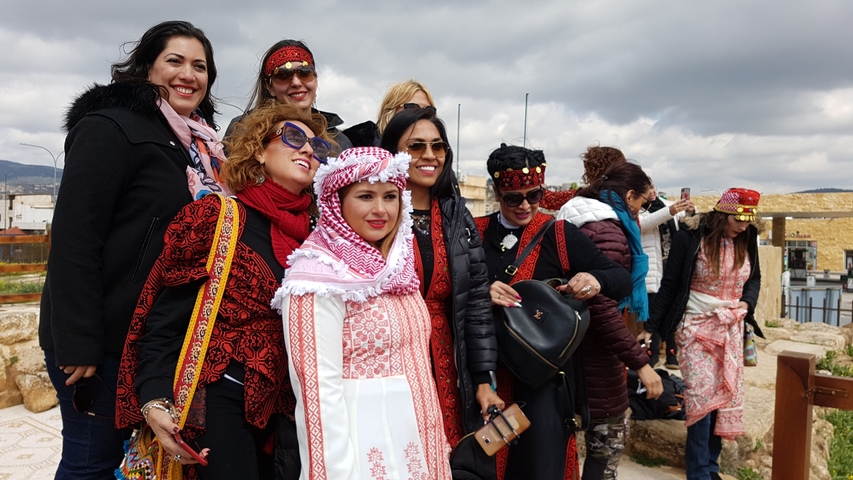       Women in traditional attire posing at a cultural site.
  