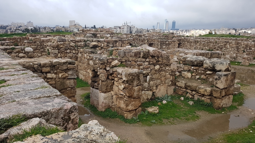      Ancient stone ruins with a city in the background.
  