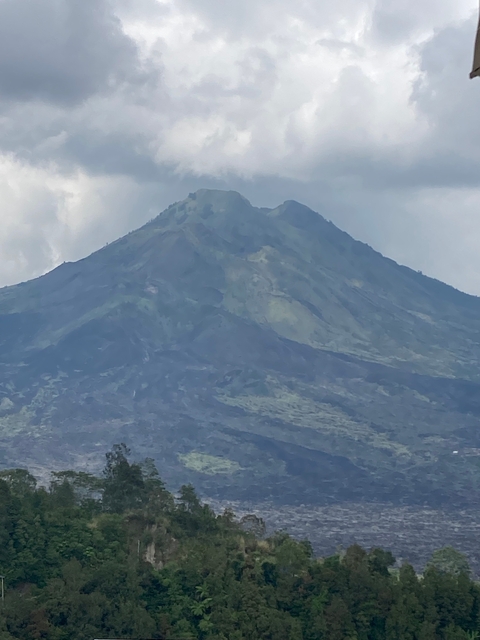 Mount Batur in the distance, partially obscured by clouds.