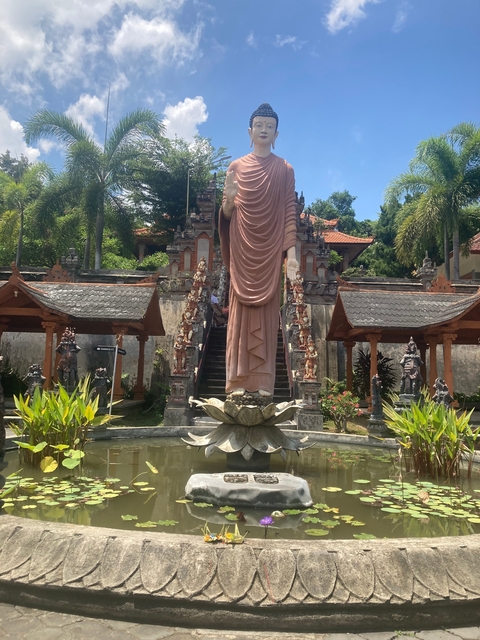 Large statue in front of traditional Indonesian temple entrance.