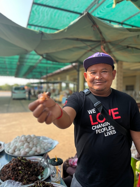       Man smiling and offering food item to the camera.
  