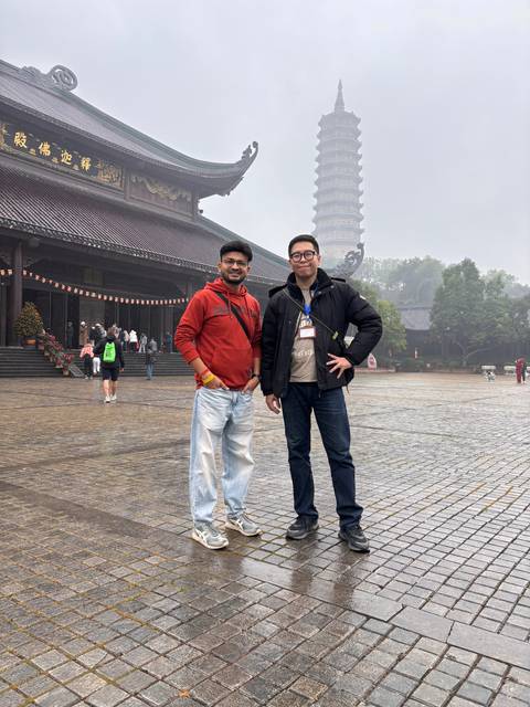       Upside-down image of two men posing in front of a pagoda.
  