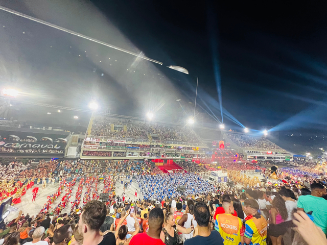 Night carnival scene with large crowd and colorful lights.