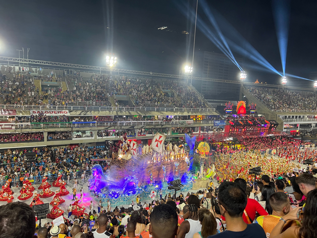       Crowded carnival scene with illuminated floats and spectators.
  