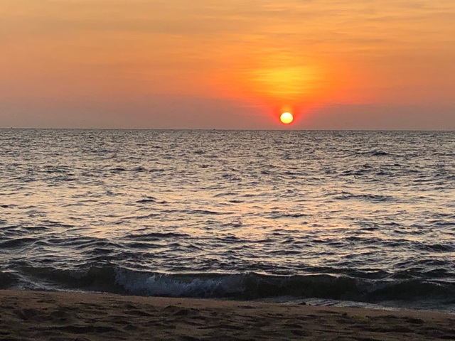       Sunset over the ocean with visible waves.
  