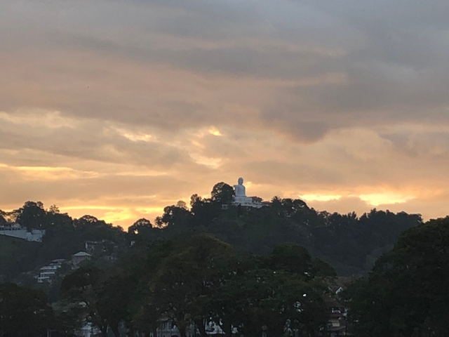       Silhouette of a hill with a structure at sunset.
  