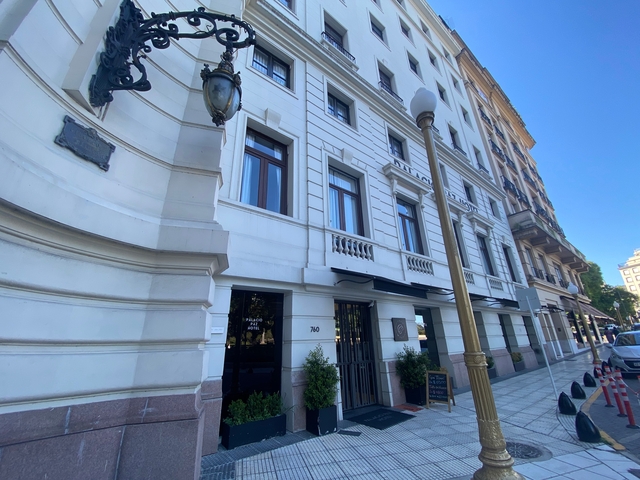       Street view of a building with shops and trees.
  