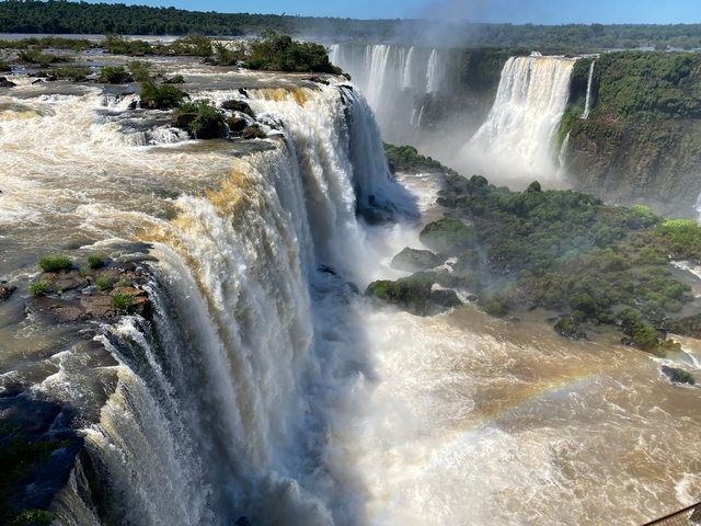       Large waterfall with surrounding greenery and a rainbow.
  