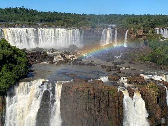       Wide view of Iguazu Falls with a rainbow.
  