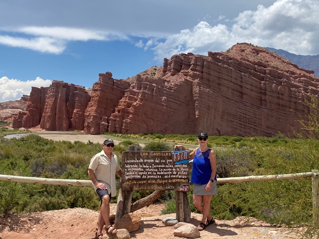       Two people posing in front of rugged red rock formations.
  