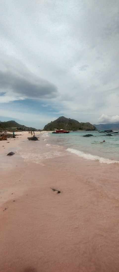       Beach with boats and mountainous background.
  