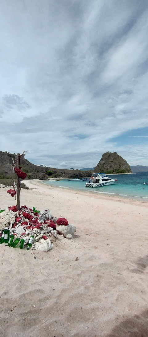 Beach with boats and a rocky hill.