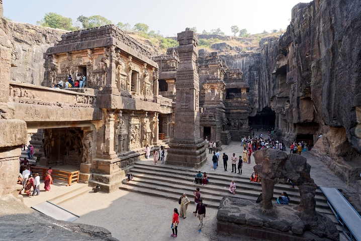       Ancient rock-cut temples with visitors exploring.
  