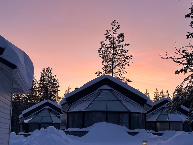       Snow-covered buildings under a pink sky at sunset.
  