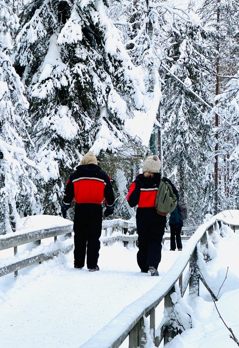       People walking through a snowy forest.
  