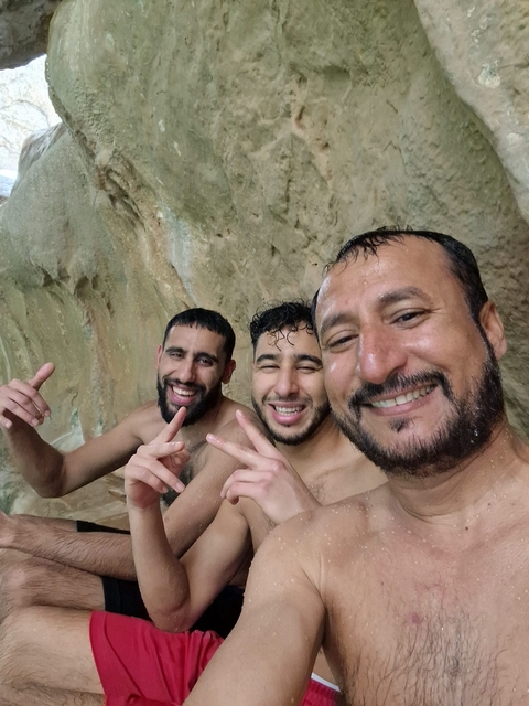 Group selfie of three men at a natural site.