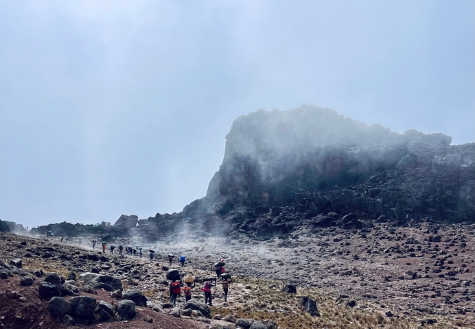 Hikers on a mountainous trail with rocky terrain.