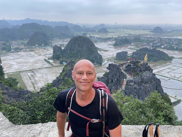 Man posing in front of a landscape with terraces.