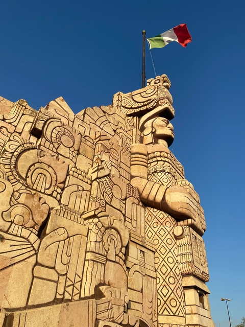       Detailed stone carvings on a large monument under a clear blue sky.
  