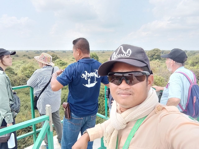 Group of people on a viewing platform with a scenic background.