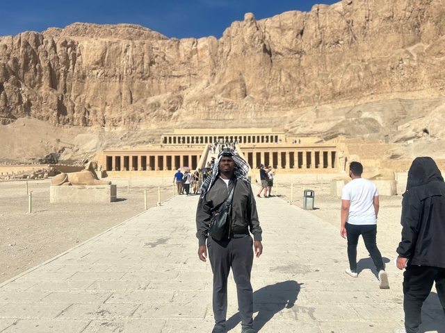      Person standing on the path leading to a large temple.
  