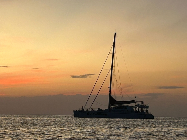 Sailing boat at sunset with an orange sky.