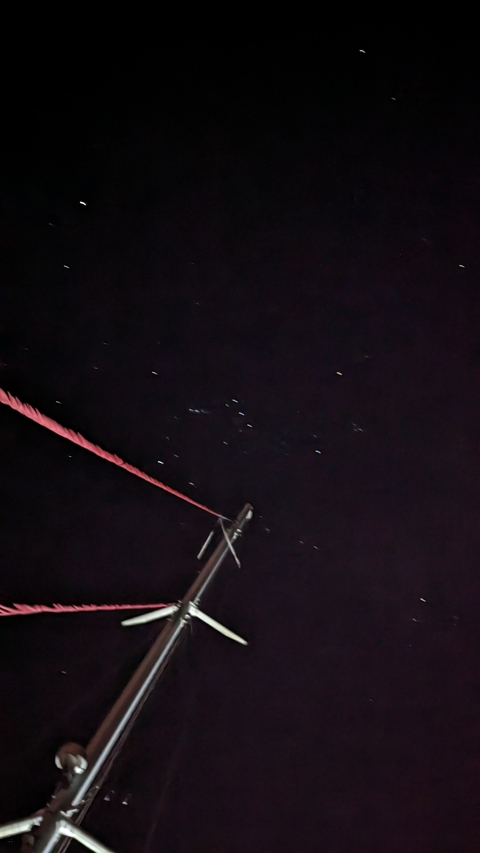       Blurred night sky with stars, a rope, and mast.
  