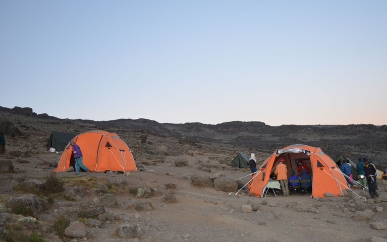 Campers setting up tents in a mountainous area.