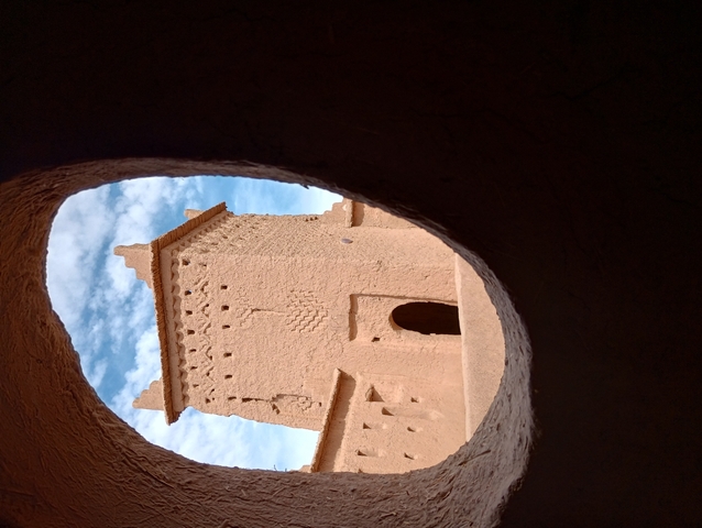       View of a desert structure through a circular hole.
  