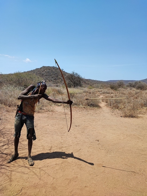 Person practicing archery in a dry landscape.