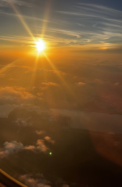       Aerial view of a river or coastline at sunset with clouds.
  