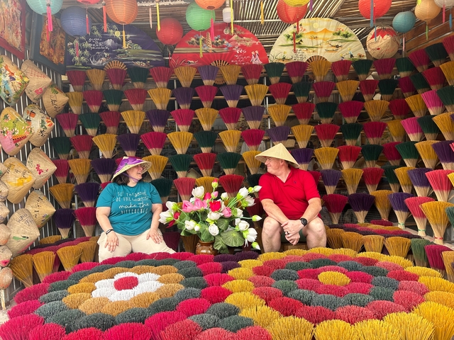       Two people sitting in a colorful incense shop.
  