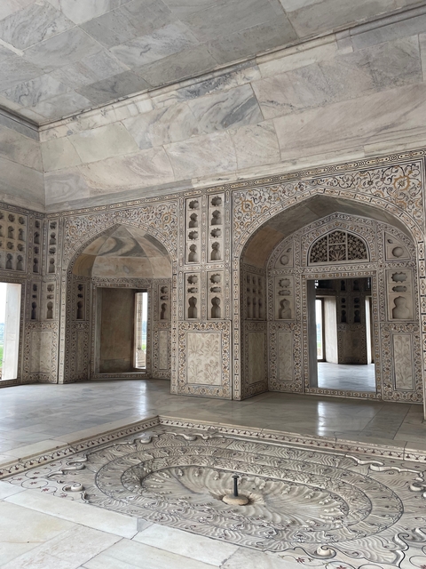 Interior of a monument with intricate carvings and arched doorways.